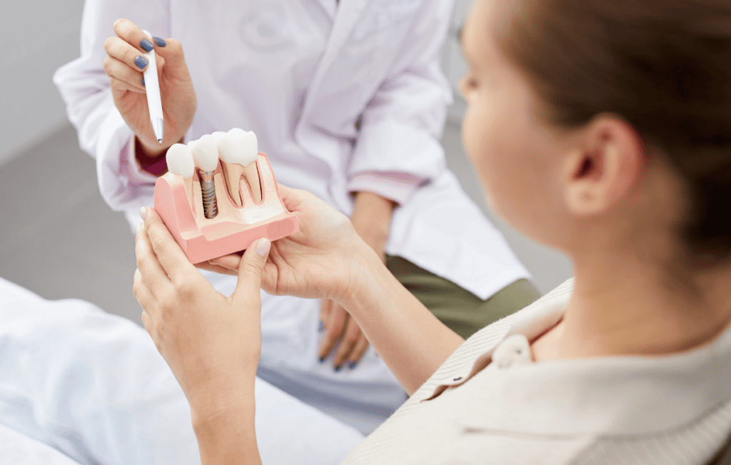 Dentist explaining a dental implant model to a patient during a consultation.