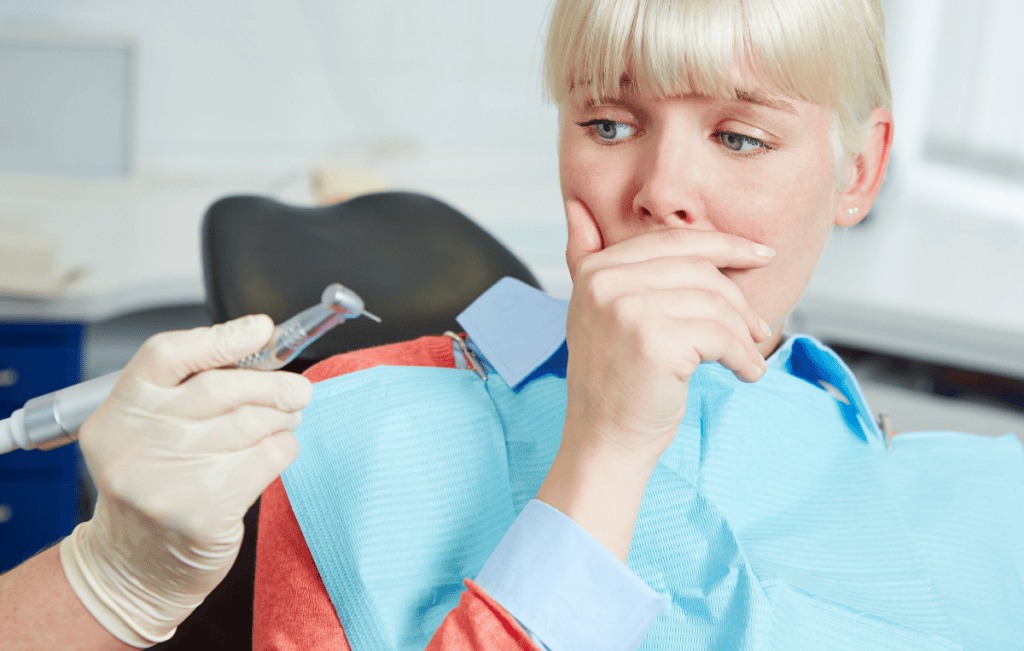 An anxious patient reacts to a dental handpiece before treatment begins.