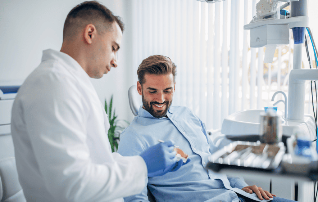 Dentist explaining a dental model to a patient during a consultation.